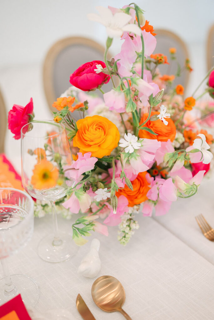 Ceremony florals in warm red, pink, and orange tones styled for a sunrise-inspired wedding at Sandy River Gardens in Troutdale, Oregon