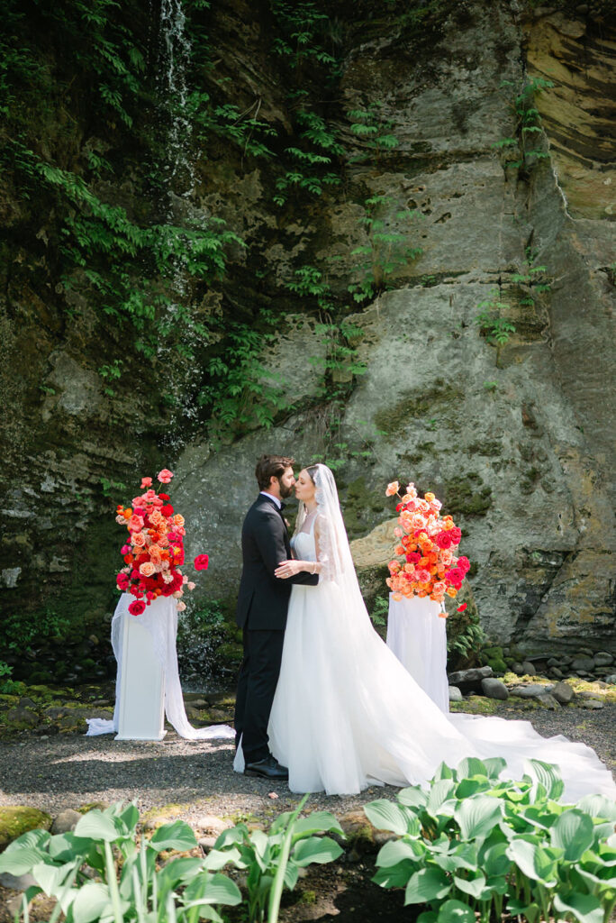 Bride and groom leaning in for a kiss during their ceremony at Sandy River Gardens in Troutdale, Oregon