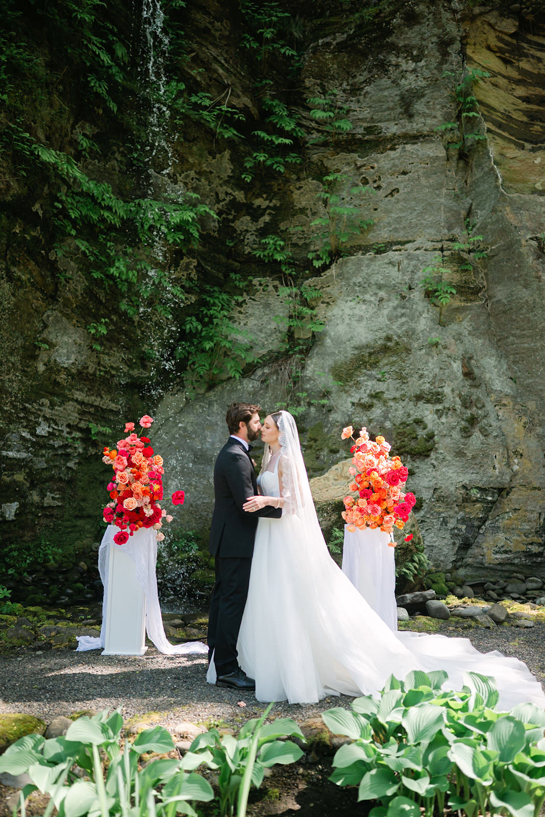 Bride and groom leaning in for a kiss during their ceremony at Sandy River Gardens in Troutdale, Oregon