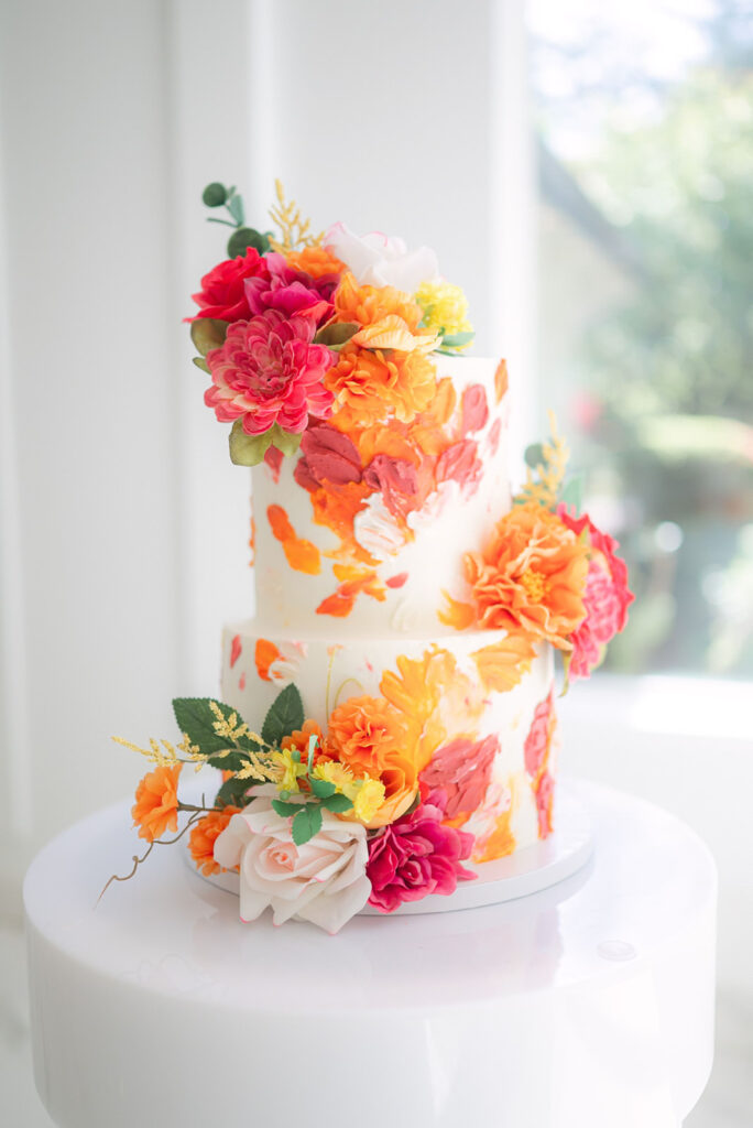 Colorful wedding cake decorated with florals at a sunrise-inspired wedding at Sandy River Gardens in Troutdale, Oregon