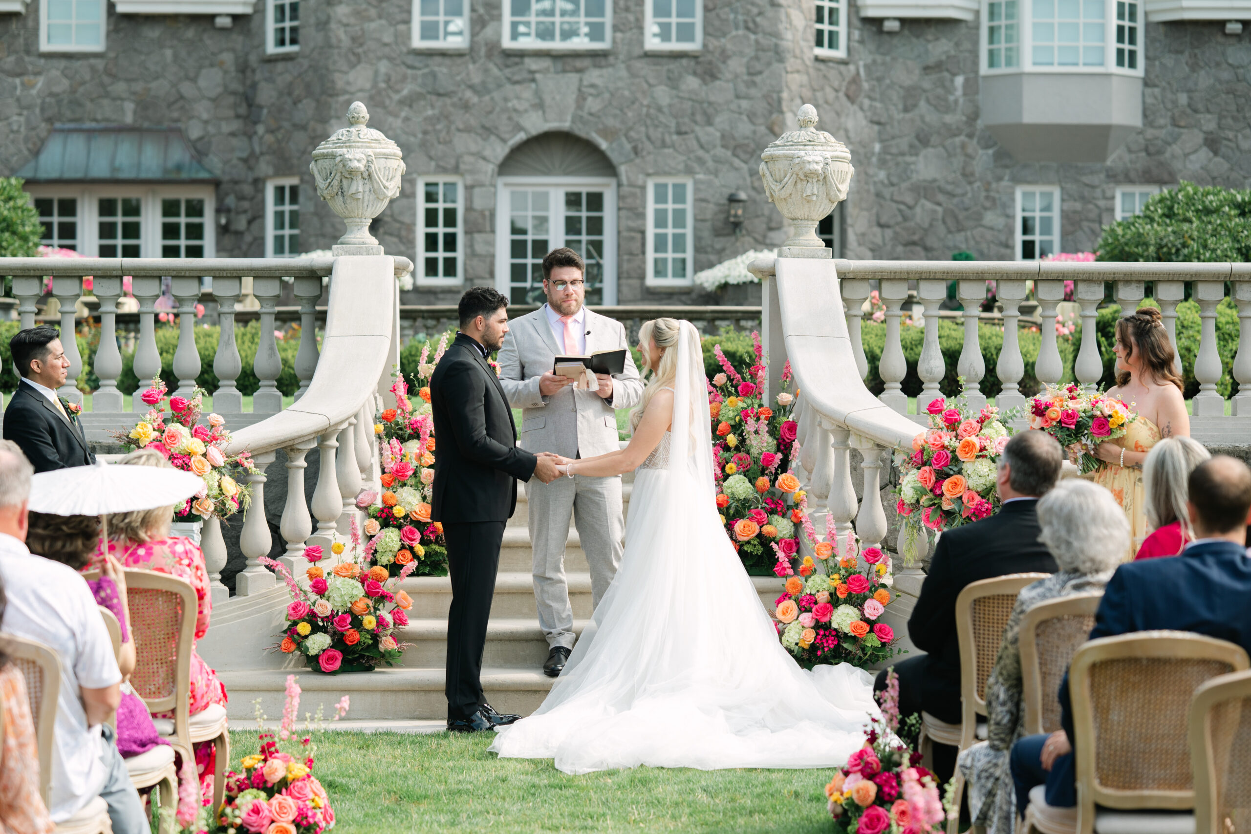 Wedding ceremony at a chateau featuring bold, colorful floral arrangements surrounding the altar.