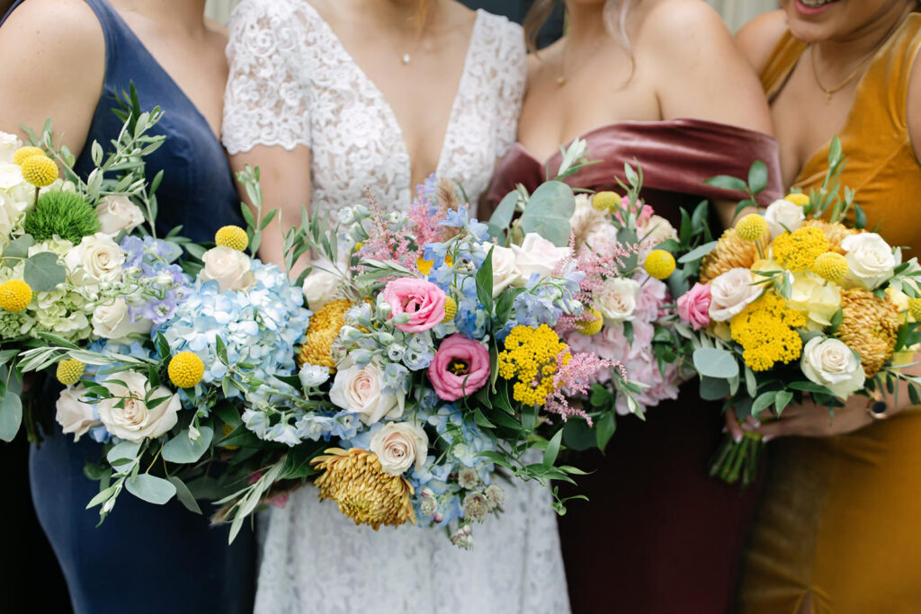 Detailed image of fall bridesmaids bouquets next to the bride’s bouquet featuring seasonal flowers in warm earthy tones for a romantic autumn wedding.