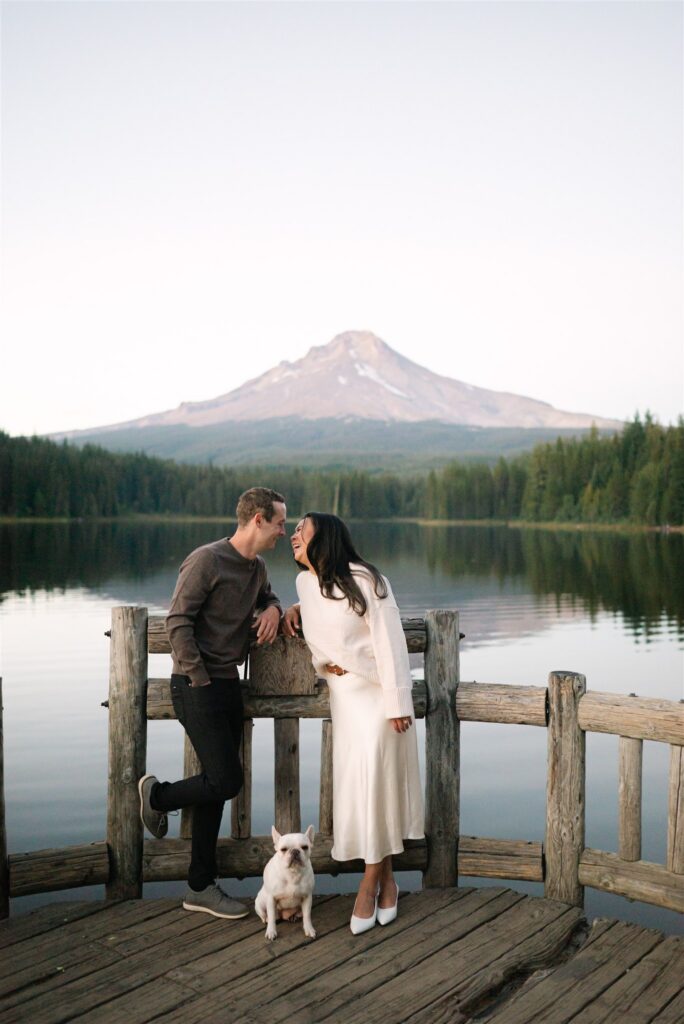 Couple sharing a moment with their dog while leaning on a fence during their engagement session