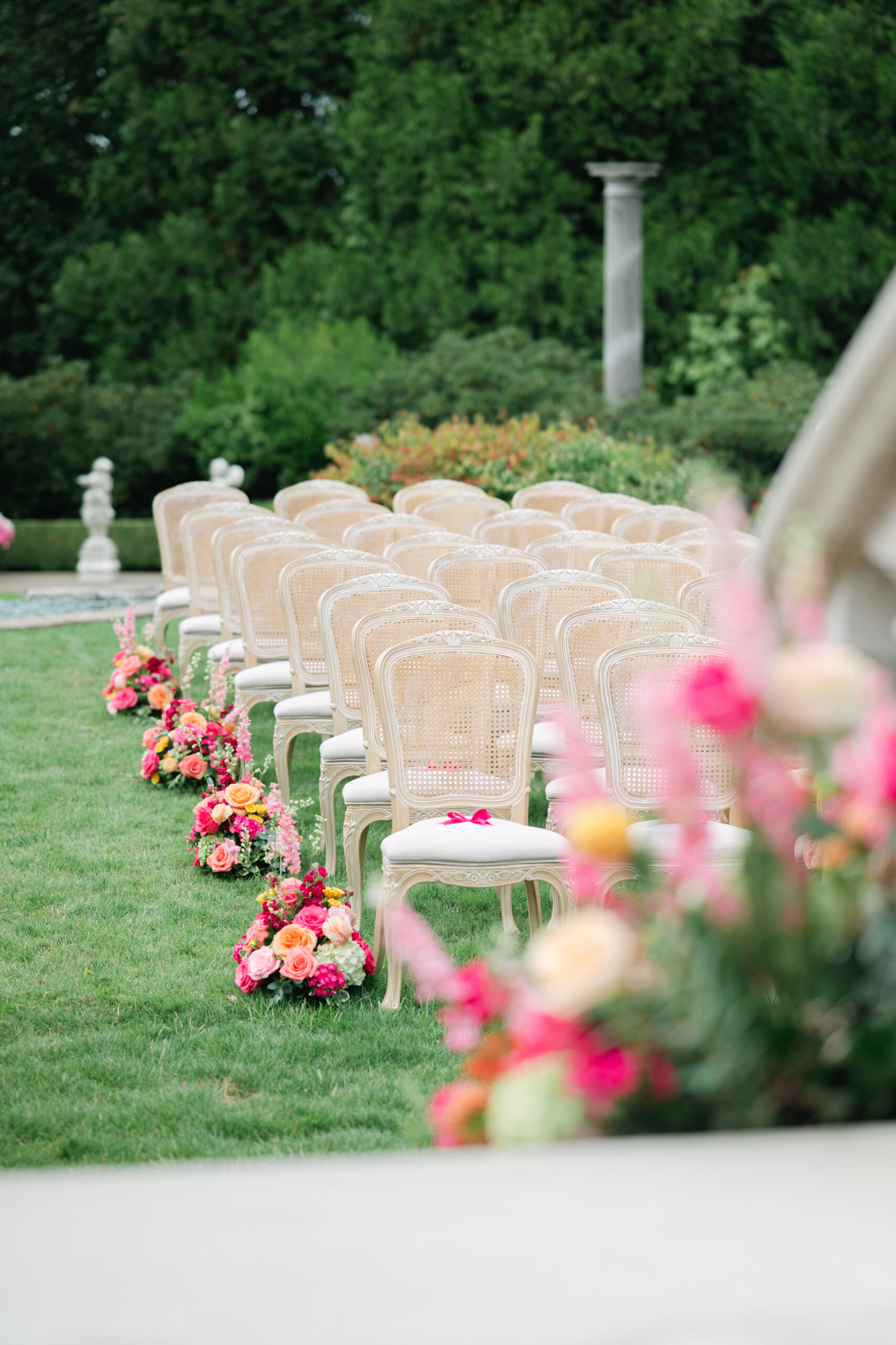 Wedding ceremony space decorated with abundant bold pink floral arrangements