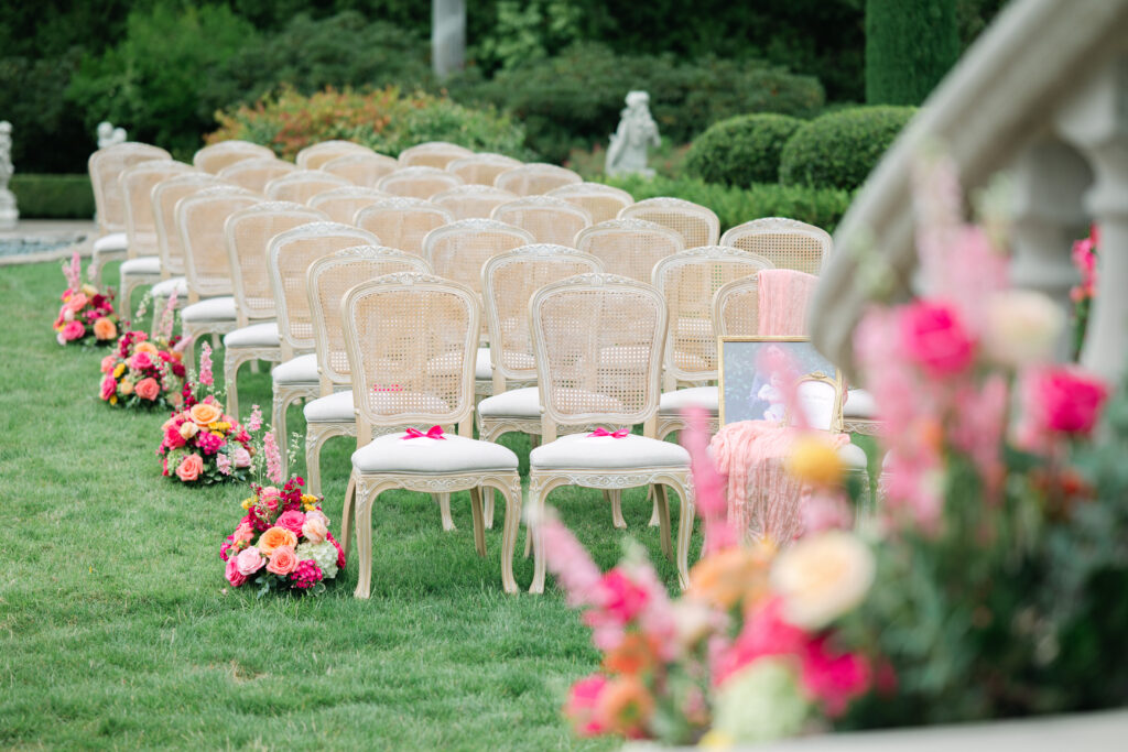 Wedding ceremony space decorated with abundant bold pink floral arrangements