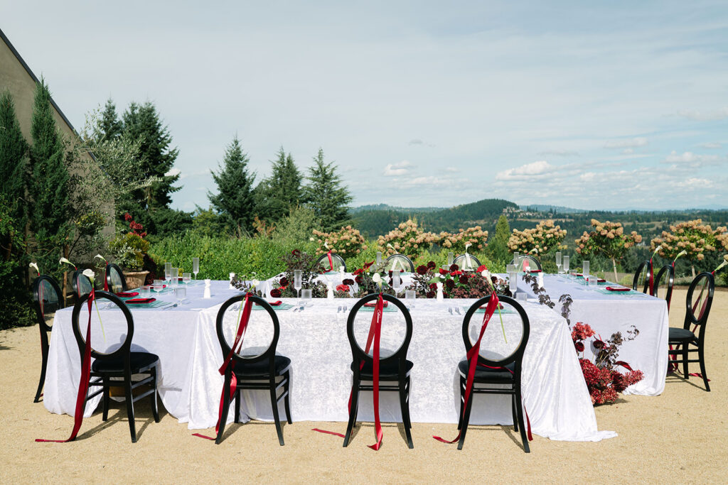 Outdoor wedding tablescape styled with bold red, white, and black details and elegant place settings