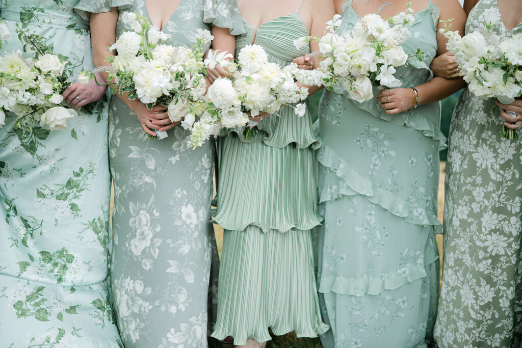 Bridesmaids in Sage Green Dresses with White Floral Bouquets Close-up of bridesmaids wearing unique sage green dresses holding white floral bouquets during the wedding day