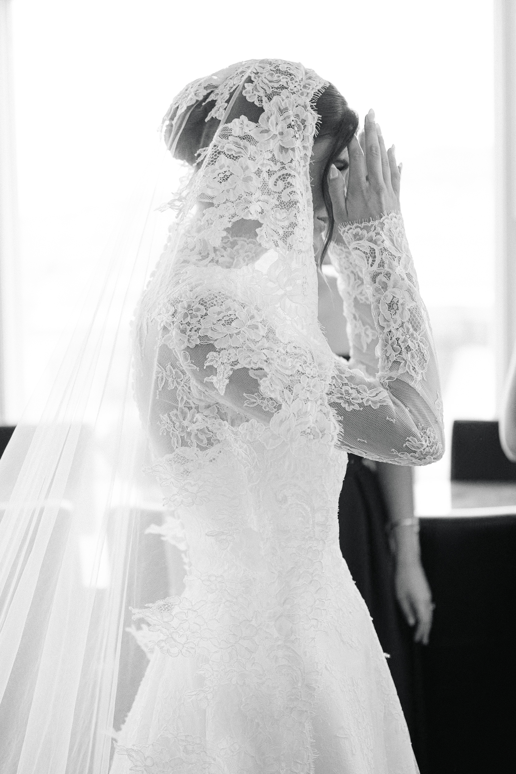 Bride adjusting her cathedral veil while getting ready before her wedding at Bay Harbor