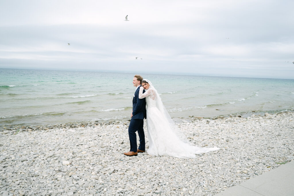 Bride and Groom Portraits at Bay Harbor on Lake Michigan Bride and groom posing along the shoreline of Lake Michigan at Bay Harbor, with birds flying in the background during their wedding portraits
